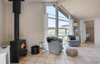 a living room with a stove and a couch and chairs at Holiday Home Tobaksvej in Blokhus