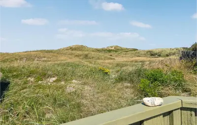 a rock sitting on a wooden bench in front of a hill at Pet Friendly Home In Pandrup With Sauna in Pandrup