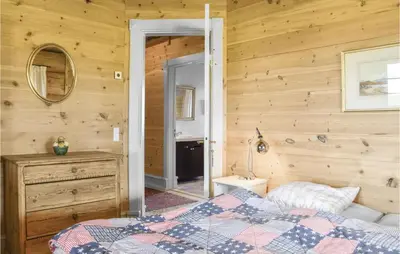 a bedroom with wooden walls and a bed and a mirror at 9 Bedroom Beautiful Home In Lemvig in Lemvig