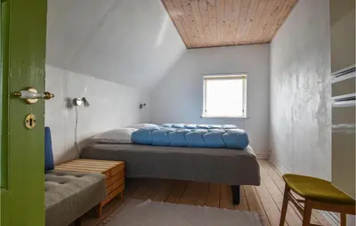 a bedroom with a bed and a window and a chair at Holiday Home Kjeldbjergvej Lemvig Iii in Lemvig