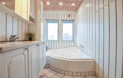 a white bathroom with a tub and a sink at Klitborgen in Harboør