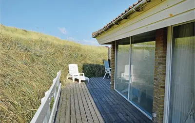 a wooden deck with two chairs on top of a house at Klitborgen in Harboør