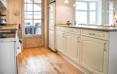 a kitchen with white cabinets and a wooden floor at Holiday Home Themisvej Harboøre Xii in Harboør