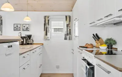 a white kitchen with white cabinets and a hallway at Holiday Home Vejlby Klit in Harboør