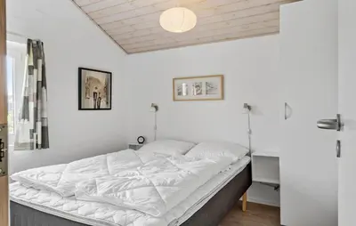 a large bed in a room with white walls at Holiday Home Vejlby Klit in Harboør