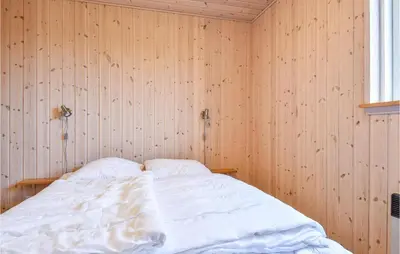 a bedroom with a bed in a wooden wall at Holiday Home Bjergehusvej in Harboør