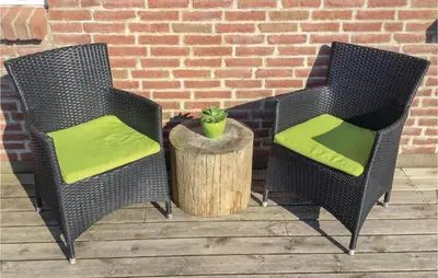 two wicker chairs with green cushions sitting on a patio at Holiday Home Doblervej Harboøre X in Harboør
