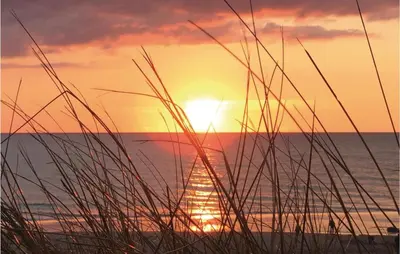 a sunset on the beach with some grass at Holiday Home Doblervej Harboøre X in Harboør