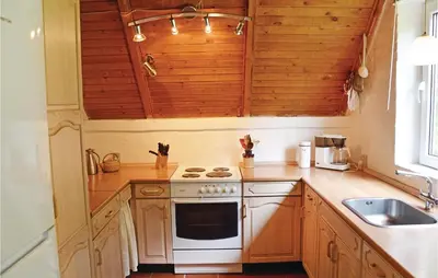 a kitchen with wooden cabinets and a white stove top oven at Humlebo in Vemb