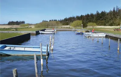 three boats are docked at a dock in the water at Humlebo in Vemb