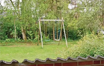 a swing set in a yard with grass and trees at Humlebo in Vemb