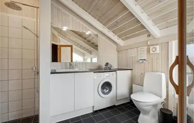 a bathroom with a washing machine and a toilet at Holiday Home Arcticvej Harboøre Iv in Harboør