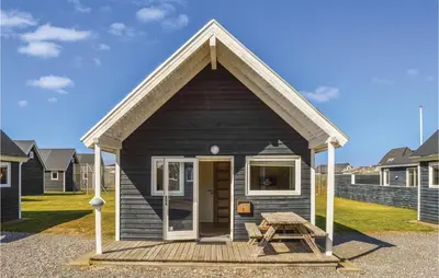 a small black house with a picnic table in front of it at Hytte 6 in Thyborøn