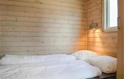 a bedroom with wooden walls and two white pillows at Hytte 6 in Thyborøn
