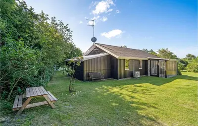 a small house with a picnic table in the yard at Fjordglimt in Vestervig