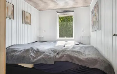 a bed in a white room with a window at Fjordglimt in Vestervig