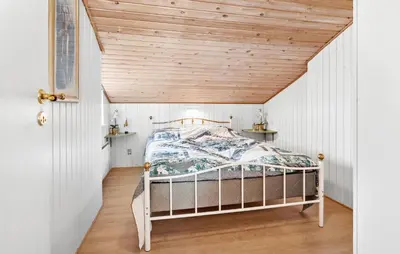 a bed in a room with a wooden ceiling at Holiday Home Kristinesvej Xii in Thisted