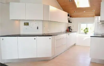 a kitchen with white cabinets and a wooden ceiling at Nice Home In Thisted With Sauna in Thisted