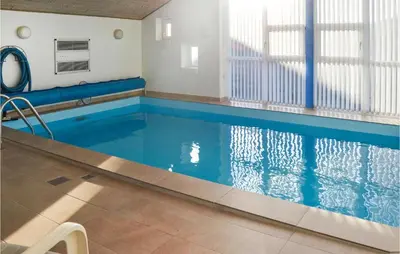 a swimming pool with blue water in a building at Nice Home In Thisted With Sauna in Thisted