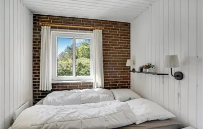 a bed in a room with a brick wall and a window at Holiday Home Clemmessti in Thisted