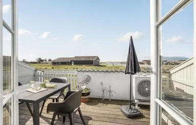 a balcony with a table and chairs and an umbrella at Holiday Home Havnevej in Vestervig