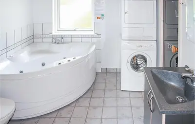 a white bathroom with a tub and a washing machine at Holiday Home Sivsangervej Vestervig X in Vestervig