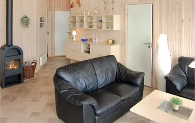 a leather couch in a living room with a fireplace at Holiday Home Søtungevej in Thisted