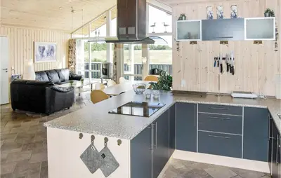 a kitchen with a counter top and a living room at Holiday Home Søtungevej in Thisted