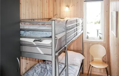 a bunk bed room with two bunk beds and a chair at Holiday Home Søtungevej in Thisted