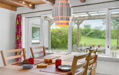 a dining room with a table and chairs and a large window at Holiday Home Årup Byvej in Snedsted
