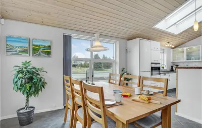 a kitchen and dining room with a wooden table and chairs at Holiday Home Kristinesvej Thisted Vi in Thisted