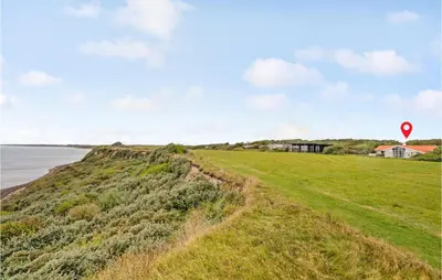 a road next to the ocean with a red marker at Beautiful Home In Vestervig With Sauna in Vestervig