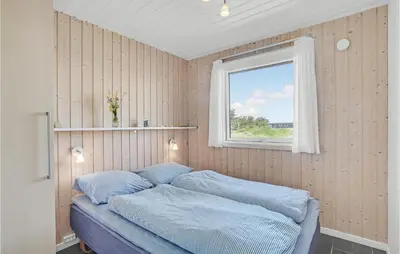 a bedroom with a bed with blue sheets and a window at Stunning Home In Thisted With Sauna in Thisted