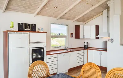 a kitchen with white cabinets and chairs and a window at Three-Bedroom Holiday Home In Thisted in Thisted
