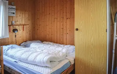 a bed in a room with a wooden wall at Holiday Home Klemsvej in Thisted