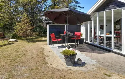 a patio with a table and chairs and an umbrella at Holiday Home Grårisvej Thisted V in Thisted