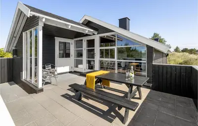 a patio with a wooden table and a bench at Holiday Home Grårisvej Thisted Vi in Thisted