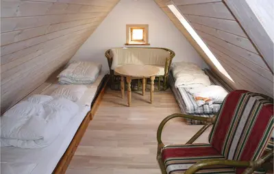 a attic room with a bed and chairs and a table at Holiday Home Grønkærvej in Thisted