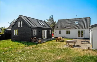 a black house and a white house and a yard at Holiday Home Stenbjerg Kirkevej in Snedsted