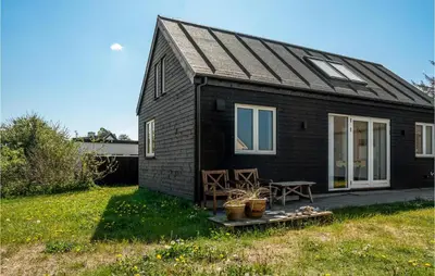 a black house with a table and chairs in a yard at Holiday Home Stenbjerg Kirkevej in Snedsted