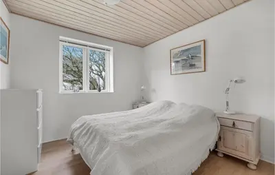 a white bedroom with a bed and a window at Holiday Home Stenbjerg Kirkevej in Snedsted