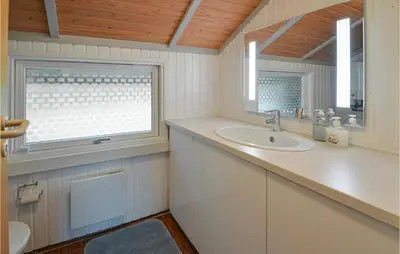 a white bathroom with a sink and a window at Holiday Home Gunhildsvej Vestervig in Vestervig