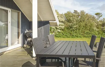a wooden table and chairs on the porch of a house at Holiday Home Gunhildsvej Vestervig in Vestervig