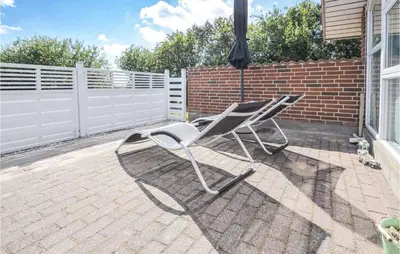 a white chair sitting on a patio with an umbrella at Holiday Home Gunhildsvej Vestervig Vi in Vestervig