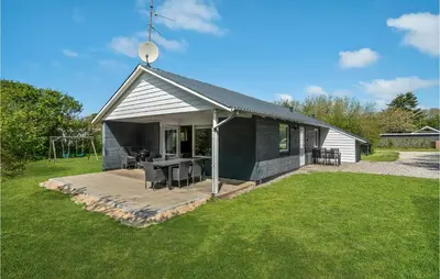 a black house with a table and chairs in a yard at Holiday Home Gunhildsvej Vestervig Xii in Vestervig