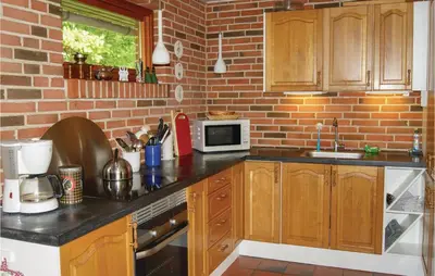 a kitchen with wooden cabinets and a brick wall at Awesome Home In Spøttrup With Wifi in Spottrup