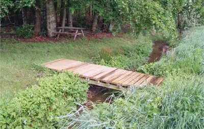 a wooden bridge over a stream with a picnic table at Awesome Home In Spøttrup With Wifi in Spottrup