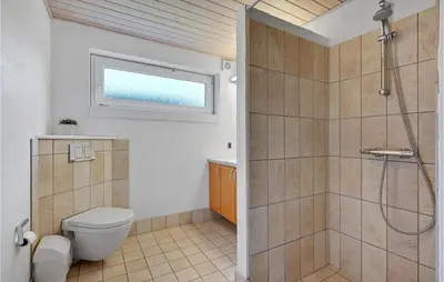 a bathroom with a shower and a toilet and a window at Stunning Home In Spøttrup With Sauna in Spottrup