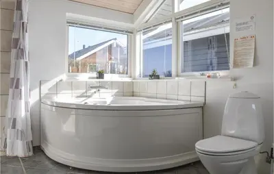 a bathroom with a tub and a toilet and a window at Holiday Home Astersvej in Lemvig