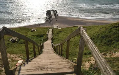 a wooden boardwalk leading to a beach and the ocean at Holiday Home Astersvej in Lemvig